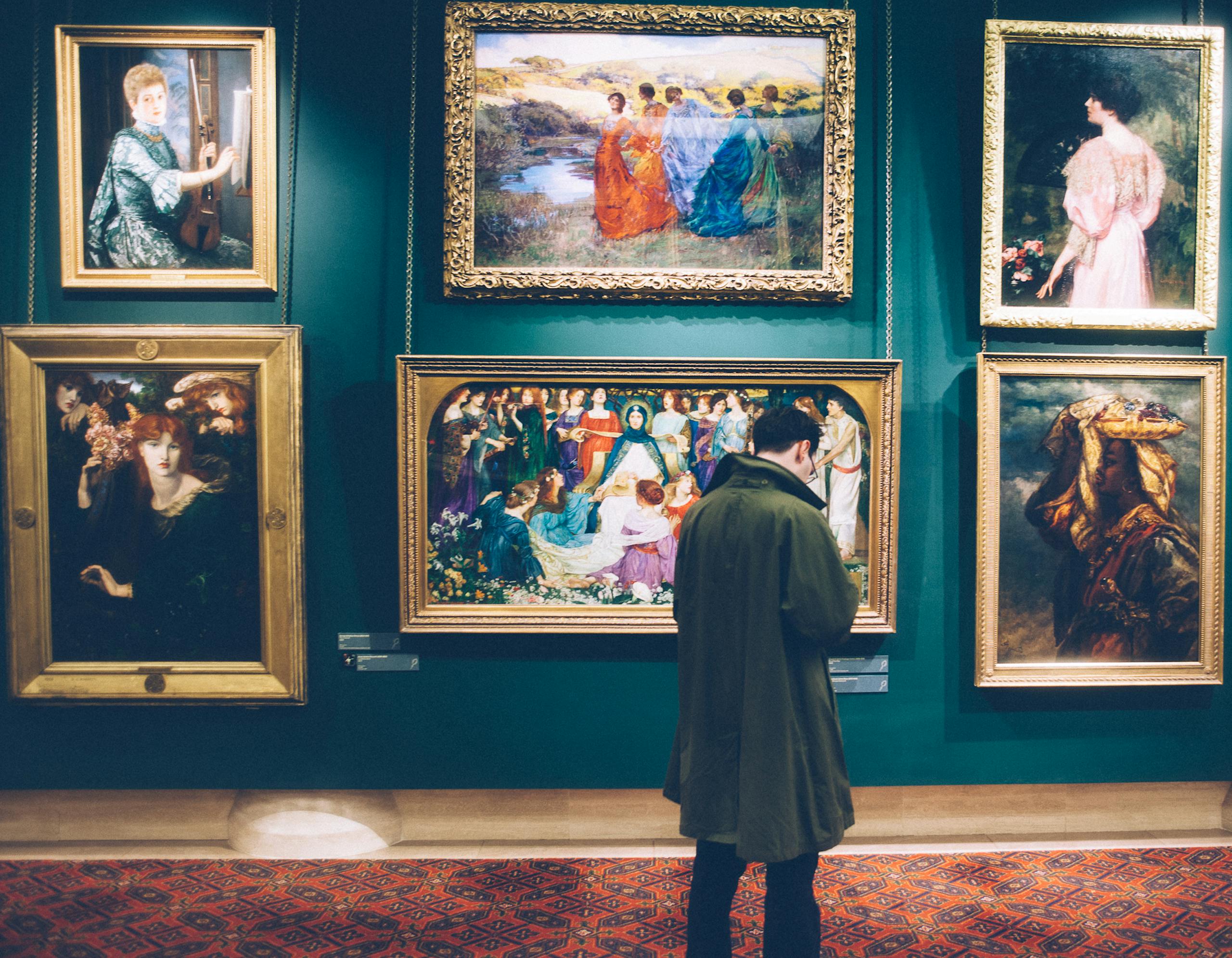 Person views classic artworks in an elegant gallery setting, exploring art history.